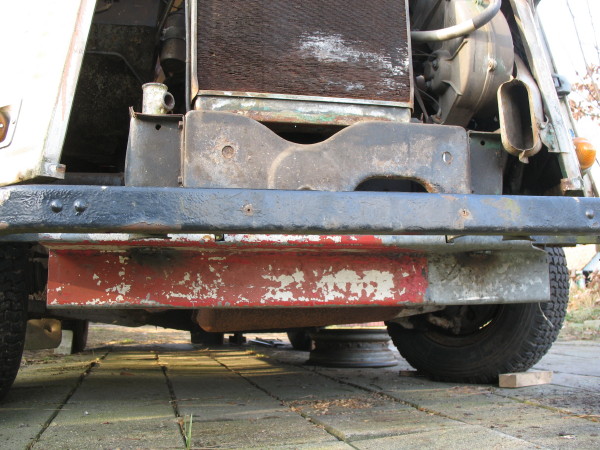 Een balkje onder de radiateur, om een krick of bok op te laten afsteunen, of om de wagen van voren op te tillen met een groter apparaat. Hij dient ook meteen als beschermplaat voor de uitlaatpot.